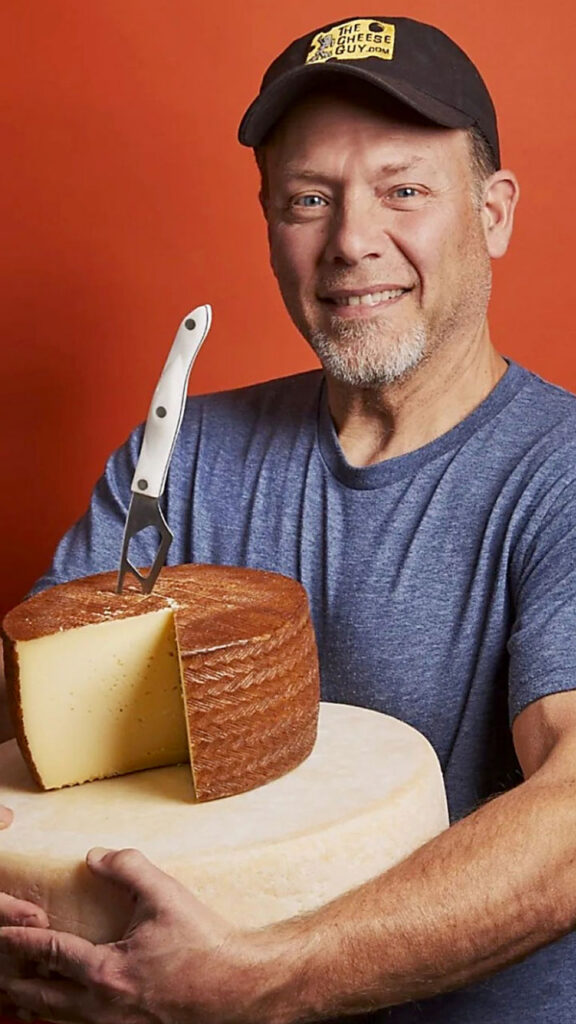 Brent Delman holds his 6-month-aged manchego wheel on top of his 2-year-aged domestic Parmesan wheel.